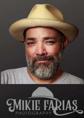 Portrait of festival photographer Mikie Farias wearing a tan fedora hat